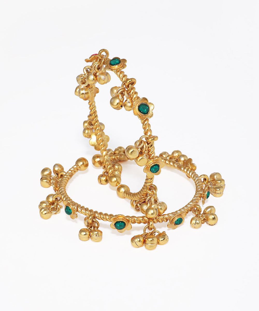 Gold bangles with green gemstones on a white background