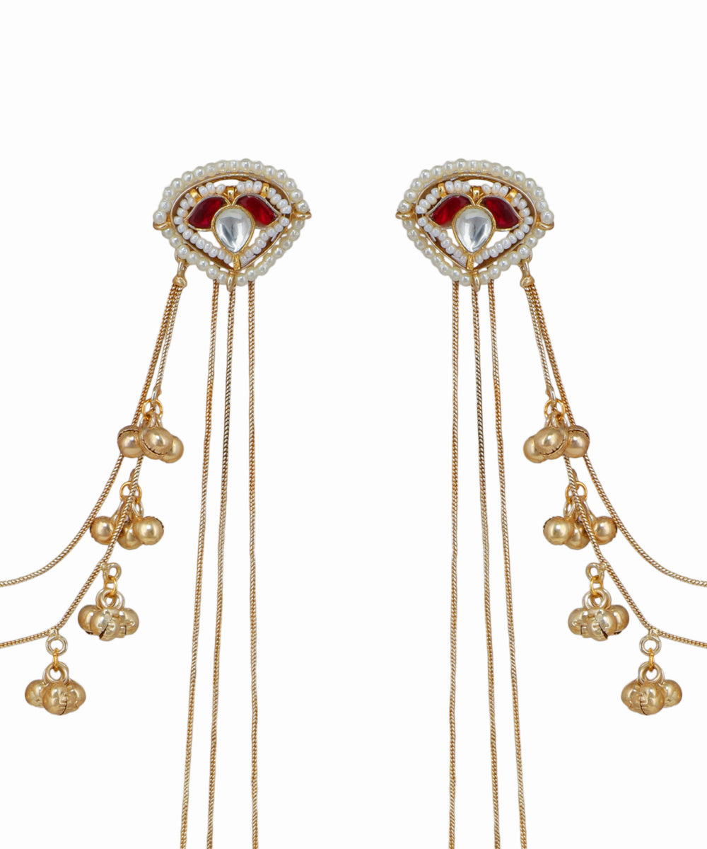 Pair of gold earrings with red gemstones and dangling beads on a white background