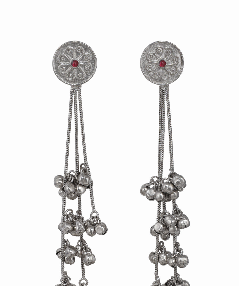 Pair of silver earrings with dangling beads on a white background