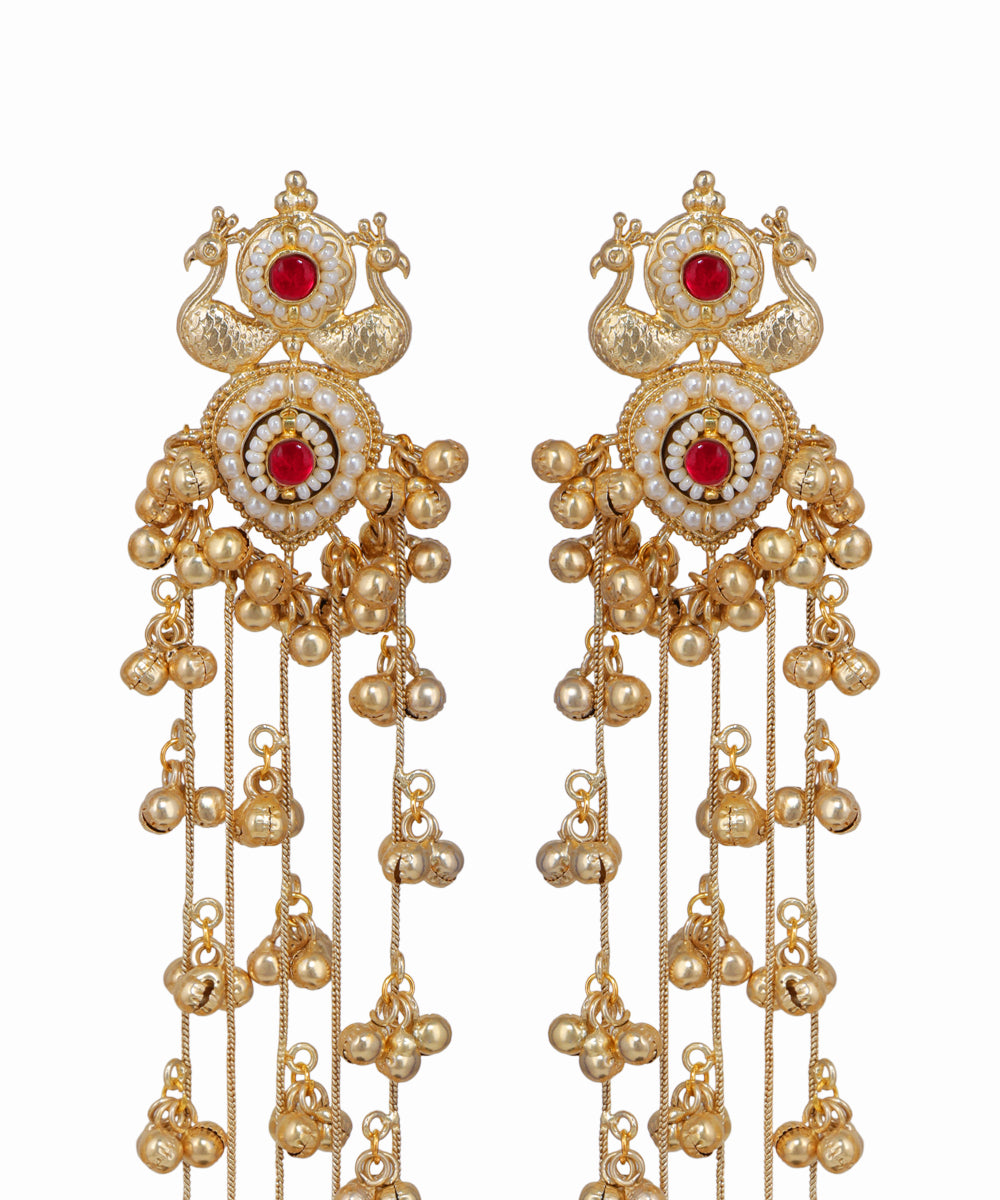 Ornate gold earrings with red gemstones on a white background