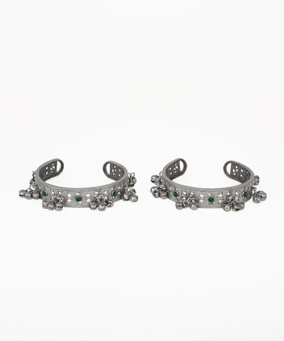 Pair of silver cuff bracelets with green gemstones on a white background