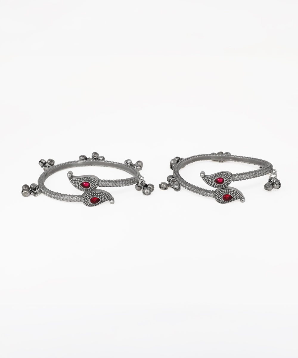 Pair of silver bangles with red stones on a white background