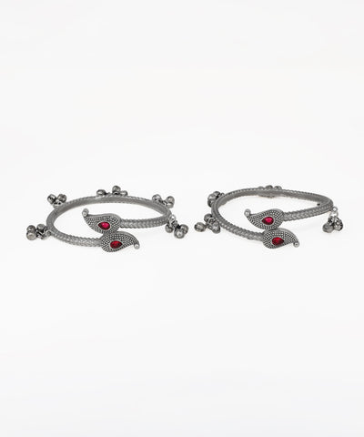 Pair of silver bangles with red stones on a white background