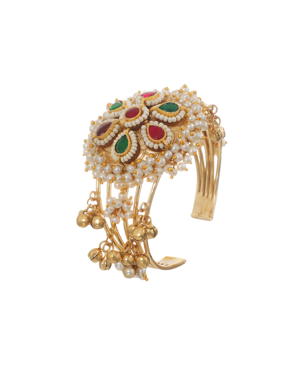 Oxidised gold-tone cuff bracelet with floral motif, red and green stones, faux pearls, and ghungroos