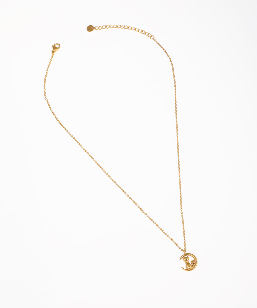 Gold-tone necklace with a crescent moon and cat pendant, featuring a small clear stone.