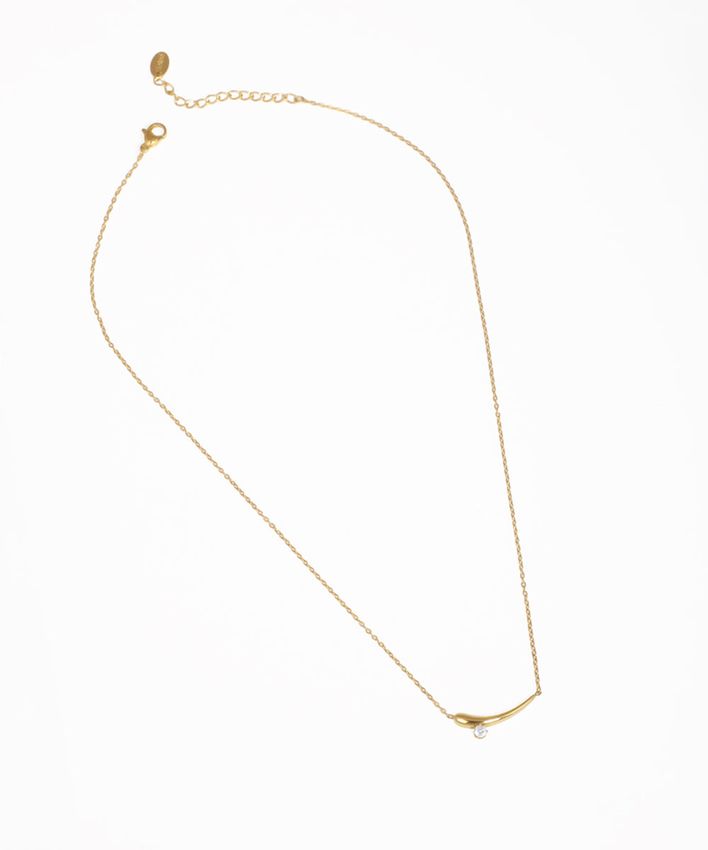 Gold-tone necklace with a curved bar pendant and small clear stone detail
