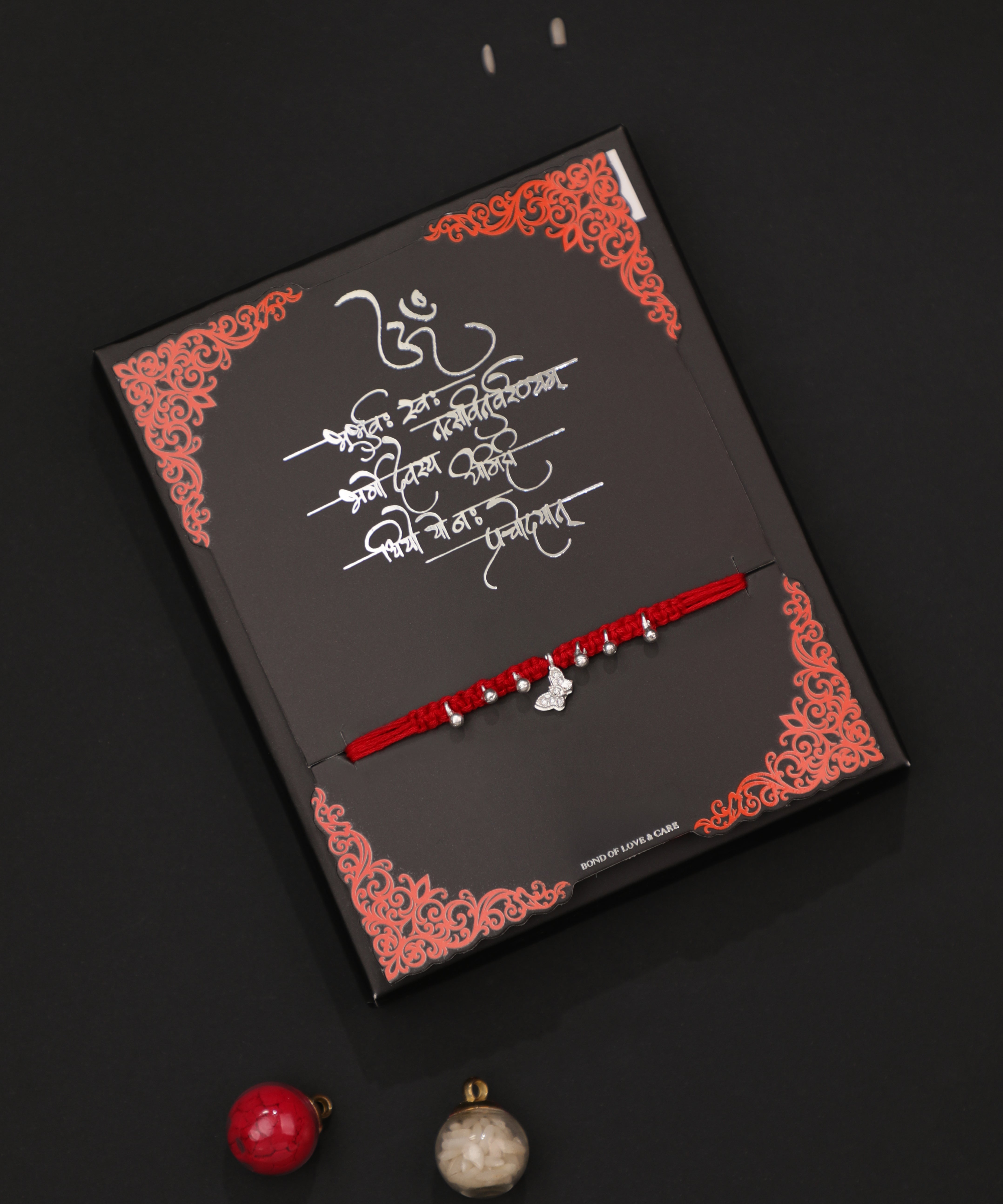 Silver-tone butterfly charm Rakhi on a red thread with small beads