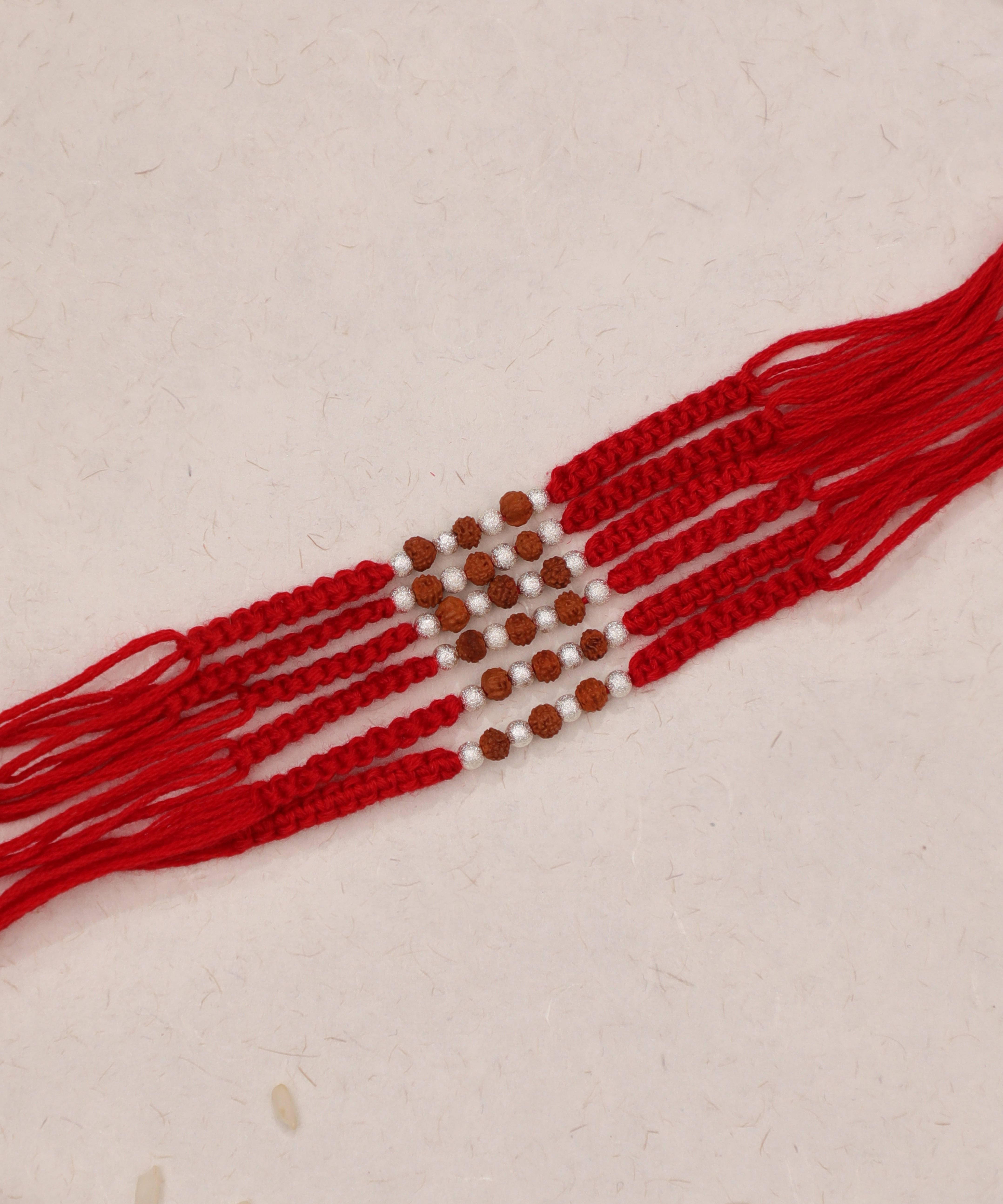 Red multi-strand Rakhi with brown and silver-tone beads, tied with thread