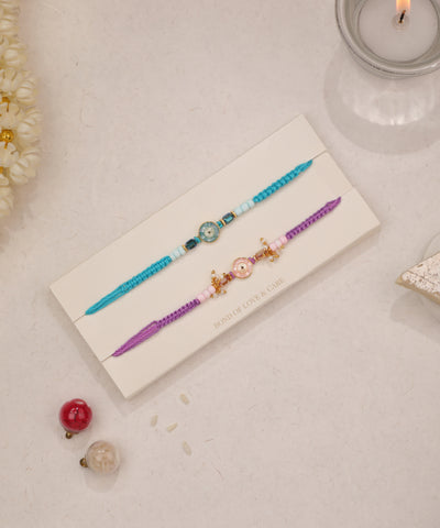 Gold-tone Rakhi set with colorful braided threads, evil eye charms, and glass beads.