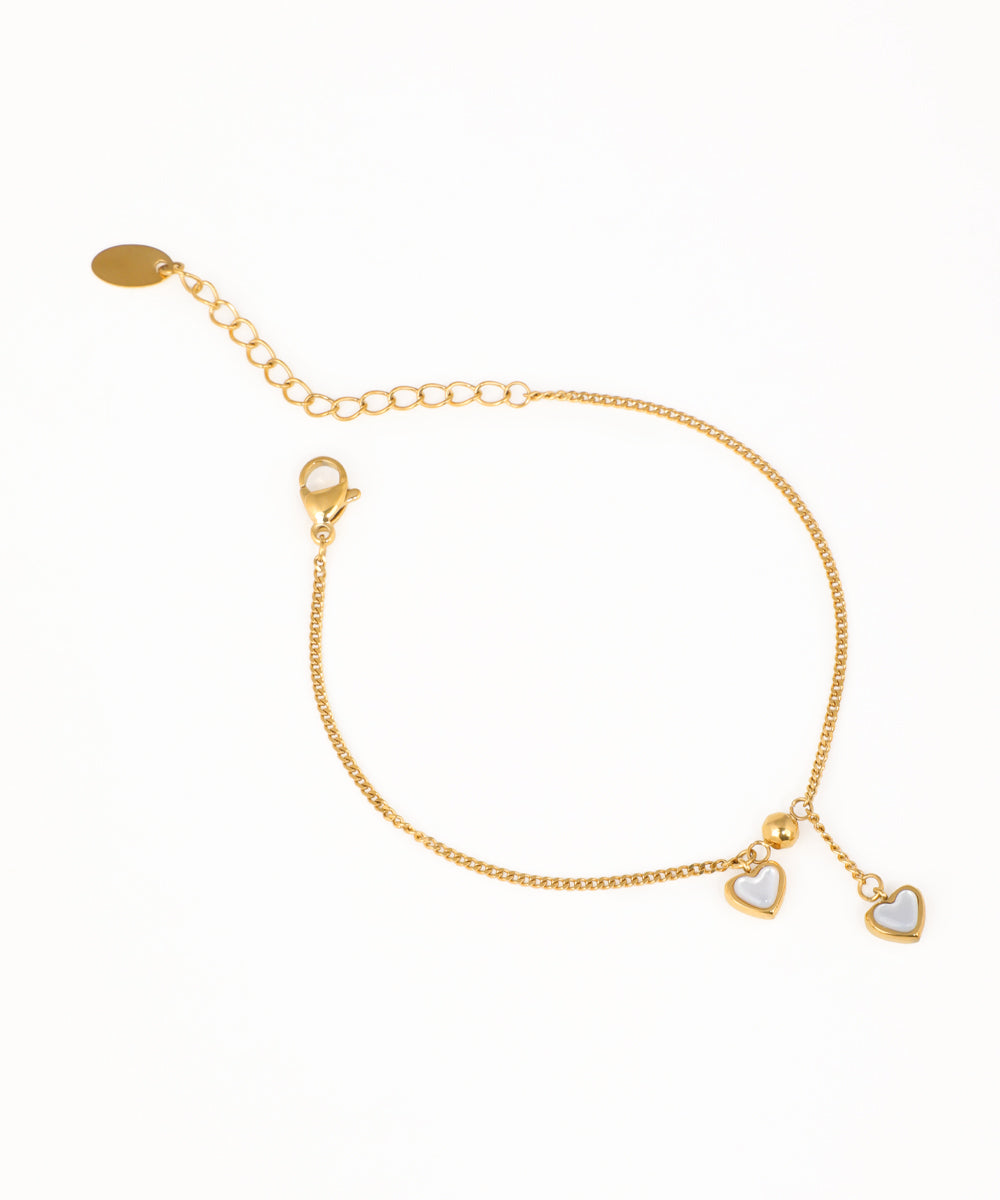 Gold-tone chain bracelet with small white heart charms and adjustable slide closure