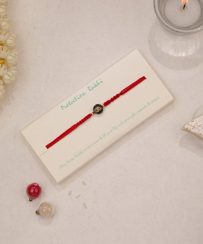 Red braided thread Rakhi with black Om symbol bead and small gold-tone accents