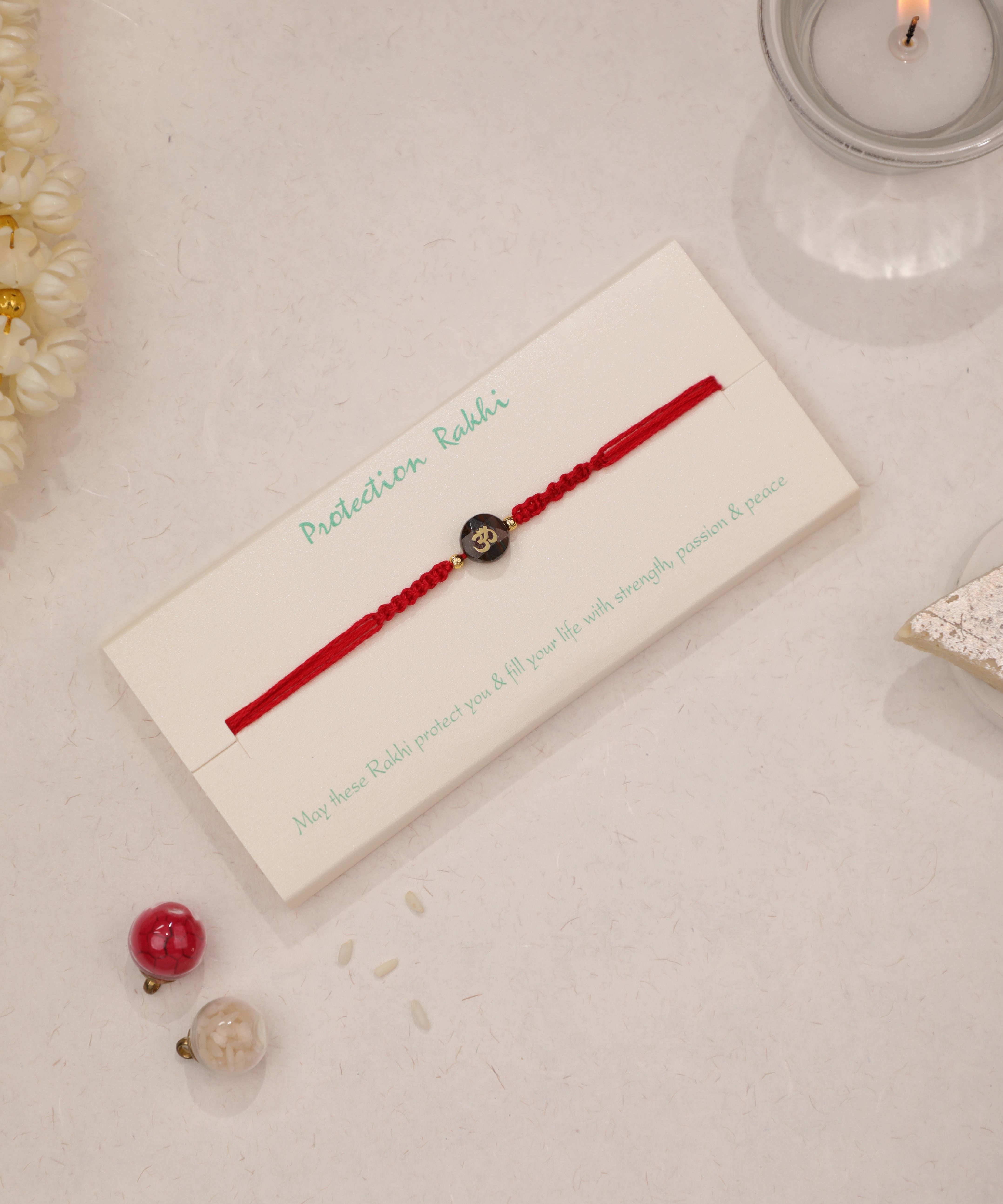 Red braided thread Rakhi with black Om symbol bead and small gold-tone accents