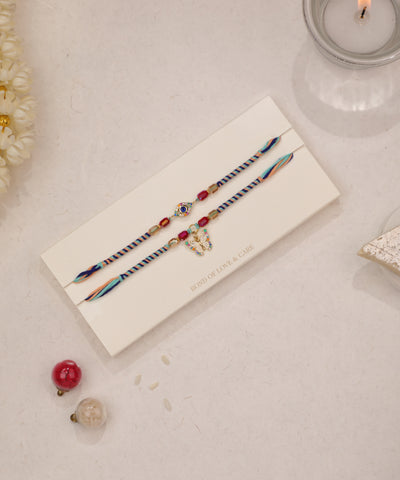 Gold-tone Rakhi set with evil eye charm, butterfly charm, and colorful glass beads on braided threads.