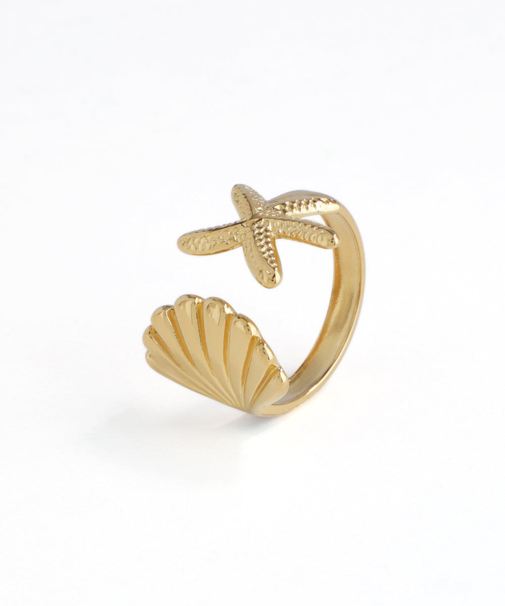Gold-tone open ring featuring a textured starfish and a fluted seashell design on a white background.