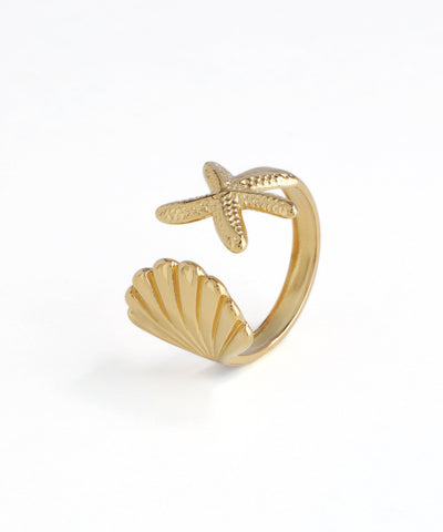Gold-tone open ring featuring a textured starfish and a fluted seashell design on a white background.