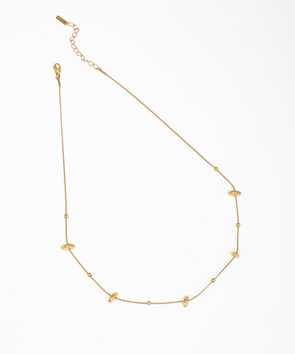 Gold-tone necklace with spaced smooth organic beads and small round accents