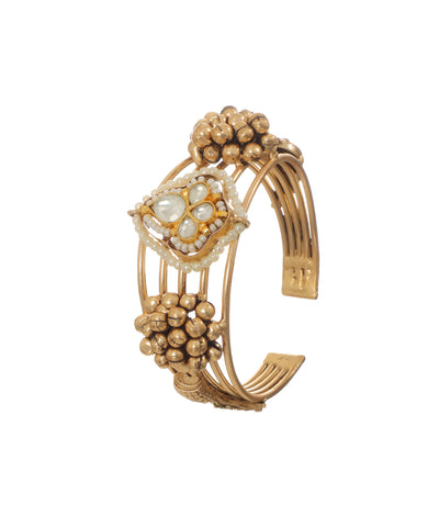 Oxidized gold-tone cuff bracelet with central kundan-style motif and faux pearls