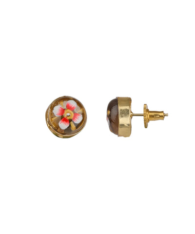 A pair of gold stud earrings on a white background, one showing a circular face with a colorful floral enamel design in pink, white, and yellow, and the other showing the side profile with a brown dome and gold post.