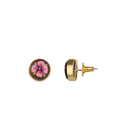 A pair of gold stud earrings shown on a plain white background, with one earring facing forward to reveal a circular floral design in pink, white, and yellow on a dark brown background, and the other shown from the side to display the gold post and backing.