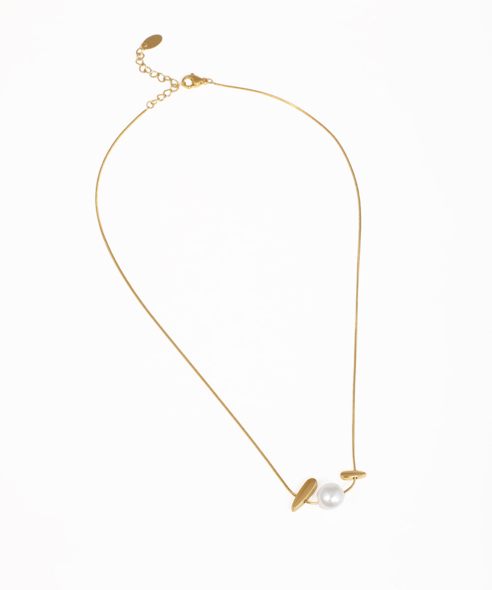 Gold-tone necklace with matte abstract bar elements flanking a white faux pearl