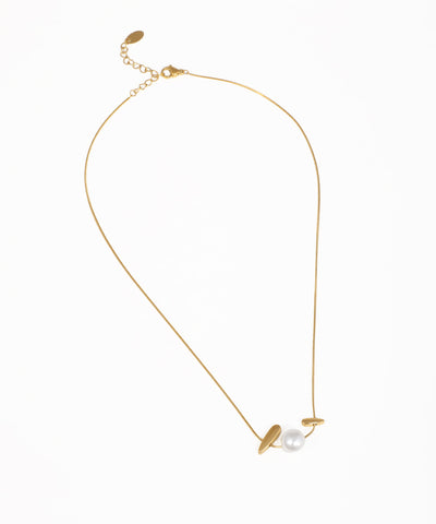 Gold-tone necklace with matte abstract bar elements flanking a white faux pearl
