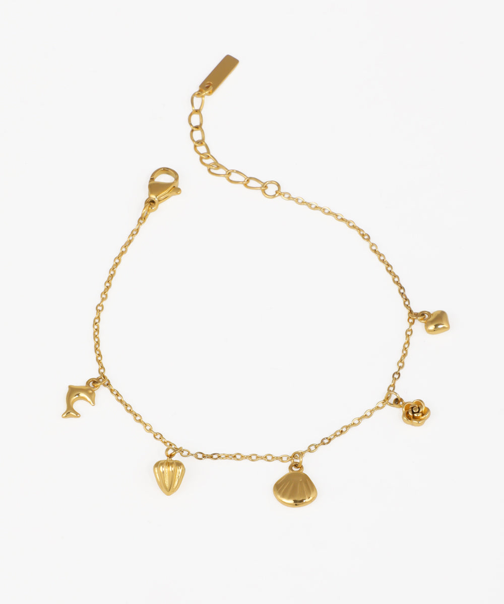Gold-tone bracelet with multiple nature and ocean-inspired charms like a dolphin, shell, and rose.