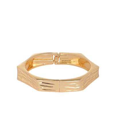 A gold-plated metal cuff bracelet with a textured, wavy pattern on the front and a polished finish, shown against a plain white background.
