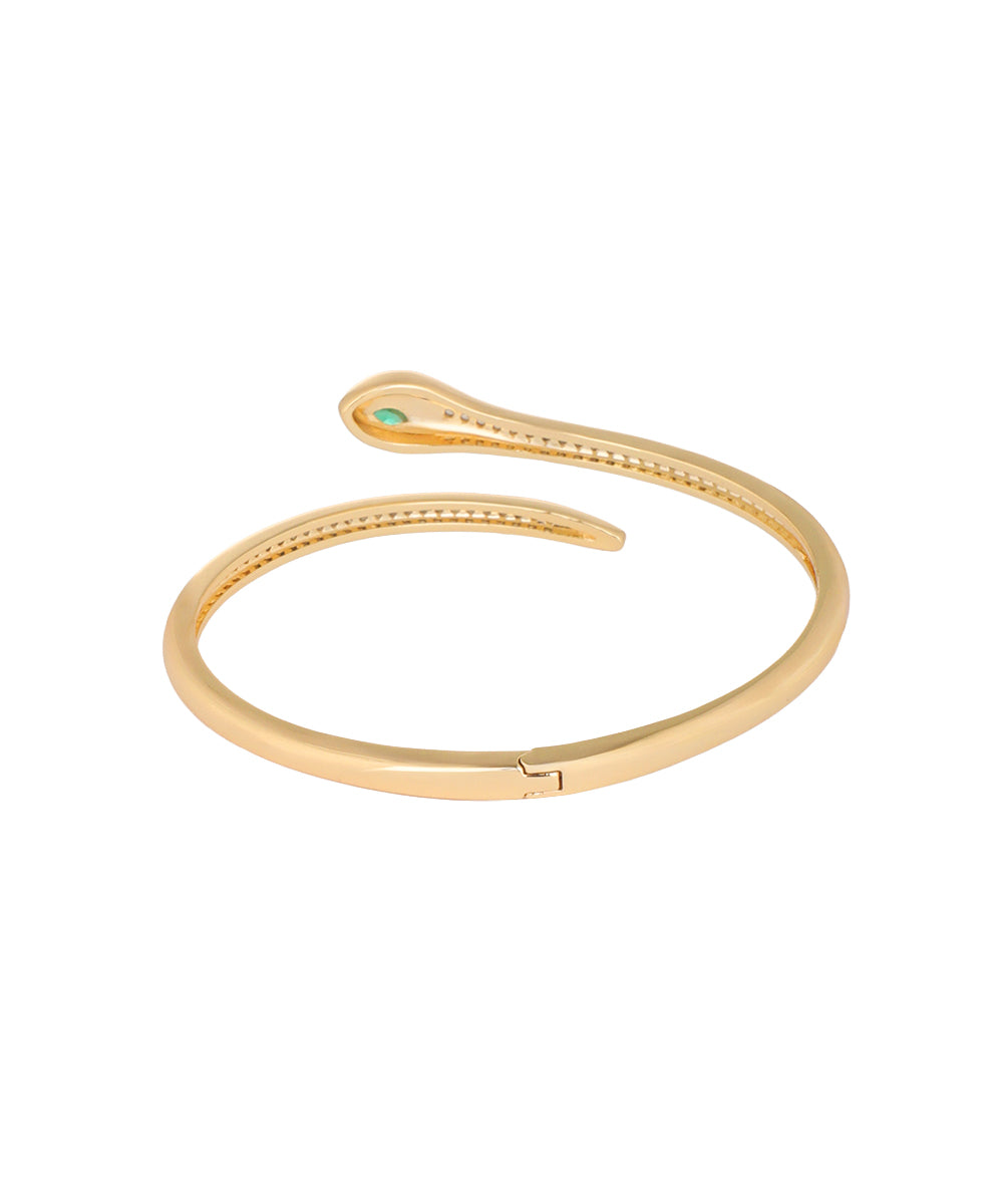 A gold-plated snake-shaped cuff bracelet with a small green gemstone accent at the tip, shown on a plain white background.
